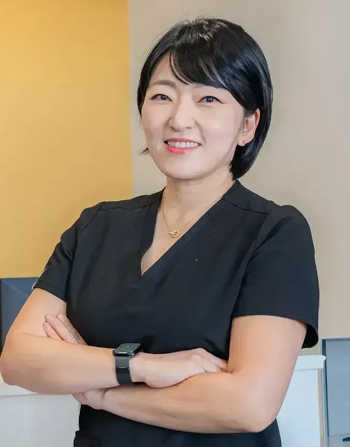 Woman in black scrubs smiling with arms crossed near 